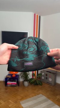 Gorro tejido en negro con patrón abstracto en color verde azulado. Cuenta con una etiqueta que dice "FOREVER." Diseño ajustado, textura suave y sin herrajes visibles.