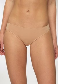 Slip bikini beige senza cuciture con forma a vita bassa, texture liscia e design minimalista. Nessun motivo o hardware visibili.
