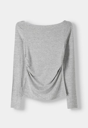 Long-sleeve, gray top with a wide neckline, featuring gathered sides creating a ruched design, made of soft, smooth fabric.