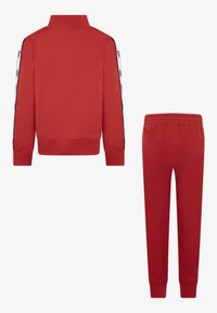 Tuta rossa con giacca a zip, colletto a coste e strisce laterali, abbinata a pantaloni con vita elastica. Realizzata in un tessuto liscio.