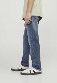 Temno modri jeans s ravnim krojem, z zbledelimi detajli. Združeni z belimi supergami, ki imajo črne črte in sive detajle.