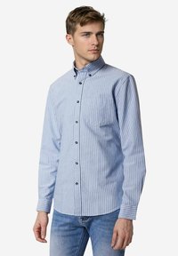 Heren overhemd met lange mouwen in lichtblauw en witte verticale strepen. De stof heeft een button-down kraag en zwarte knopen. Eenvoudige borstzak.