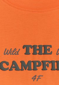 Tissu orange avec texte noir en relief indiquant « Wild THE CAMPFIRE 4F » près d'un col arrondi.