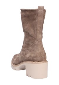 Botas de tobillo de ante marrón con tacón bloque. Presentan una textura suave y una punta redonda, con detalles de costura a lo largo de las costuras y la suela.