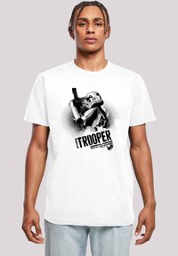 Balts kokvilnas T-krekls ar melnu grafisko attēlu, kurā redzams stormtrooperis, kas tur blasteri, ar lieliem burtiem zem tā rakstīts "STORM TROOPER".