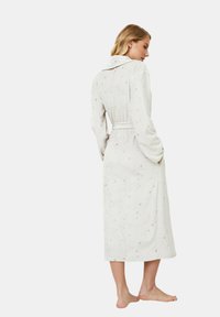 Robe bianco con motivo a stelle argento, maniche lunghe e vita con cintura. Tessuto morbido, lunghezza al ginocchio, con colletto e tasche.