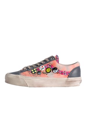 Sneaker basse con tessuto rosa e accenti grigi, decorate con spille colorate tra cui yin-yang e il logo Vans sul lato.