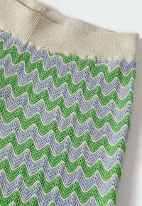 Tissu tricoté avec un motif ondulé en vert et bleu clair, featuring une taille côtelée beige. Texturé avec des détails complexes et une finition douce.