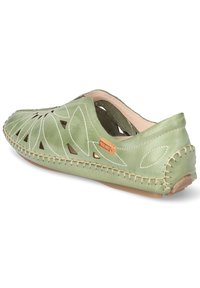 Zapato verde de cuero tipo slip-on con recortes en forma de hoja, costuras de color claro y suela texturizada; cuenta con una etiqueta de logo en el lado.