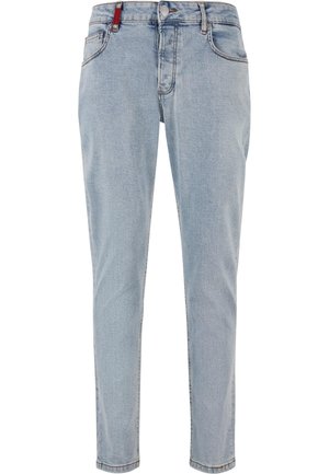 Jasnoniebieskie jeansy o prostych nogawkach z przednimi kieszeniami, szlufkami na pasek, zapięciem na guzik i małą czerwoną metką po prawej stronie.