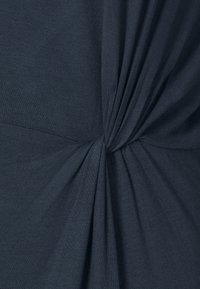 Mörkblå tajt t-shirt i mjukt tyg, med en vriden design vid midjan som skapar en texturerad look.