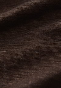 Tessuto marrone con una consistenza a trama fine, che mostra fili morbidi e leggermente elastici, adatto per abbigliamento o rivestimenti.