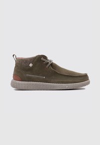 Botas de tobillo de ante verde oliva con suelas de goma gris texturizadas, detalles en cuero marrón y cordones contrastantes. Interior forrado con un tejido suave.
