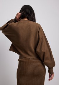 Maglione marrone a maglia con una vestibilità rilassata, maniche larghe, texture a costine e un design cropped, abbinato a una gonna a costine coordinata.
