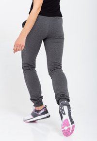 Szare spodnie dresowe o zwężanym kroju, z miękką fakturą i elastycznym pasem. Noszone z wielokolorowymi butami sportowymi.