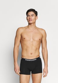 Schwarze Boxershorts mit einer figurbetonten Passform, aus weichem Baumwollmaterial und einem elastischen Bund mit dem weißen Logo "URBANCLASSICS".