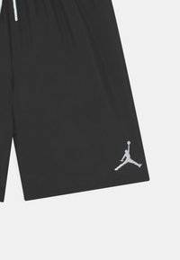 Pantalones cortos deportivos negros hechos de una tela suave con una cintura elástica, que presentan un logo Jumpman blanco en la parte inferior izquierda.