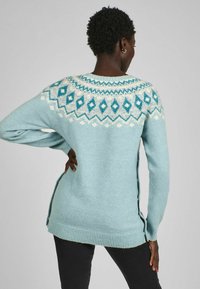Pulover tricotat de culoare bleu deschis cu un design tip yoke în nuanțe de turcoaz și modele cu diamante albe. Include nasturi pe laterale și tiv cu zimți.