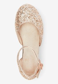 Goldene Glitzer-Ballettschuhe mit runder Zehenpartie, glattem Innenfutter und zartem Knöchelriemen. Strukturierte Glitzerpartikel bedecken die obere Fläche.