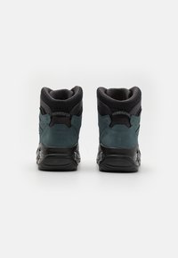 Sneakers alti con una parte superiore in suede e rete di un verde scuro, dettagli neri, collo imbottito e suola in gomma testurizzata.