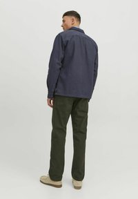 Navy button-up shirt with a collar and long sleeves, paired with green cargo pants. The outfit features a relaxed fit and visible stitching details.