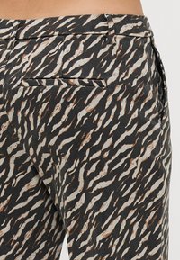 Pantaloni a fantasia neri e crema con un design ondulato, dotati di una tasca posteriore singola e una vestibilità sartoriale in vita.