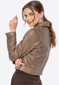 Braune Lederjacke mit figurbetontem Design, Schulterklappen und einer strukturierten Oberfläche. Sie hat schräge Nähte und eine verkürzte Länge.
