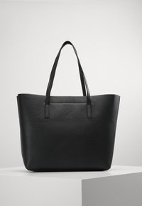 Un sac fourre-tout en cuir noir avec une finition texturée, deux poignées solides, un dessus ouvert et une forme rectangulaire spacieuse. Design minimaliste sans embellissements.