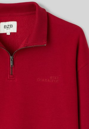 Sweat-shirt à col demi-fermeture éclair rouge, col côtelé, avec "BEST CHARACTER" brodé sur le côté gauche de la poitrine. Texture de tissu doux.