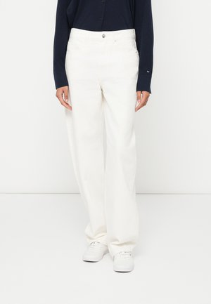 Calças brancas de perna larga com cintura alta, feitas de um tecido suave, com fecho de botão frontal e bolsos laterais. Usadas com sapatos brancos.