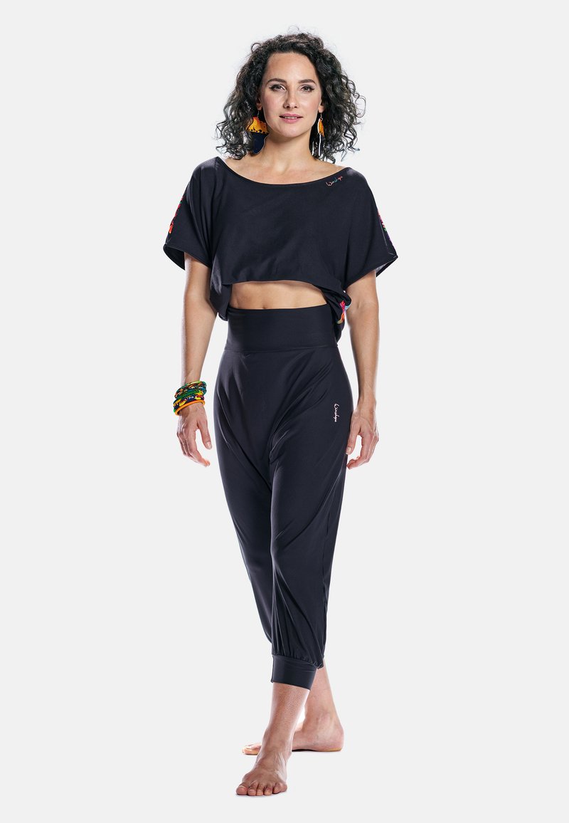 Top cropped noir avec des manches larges, associé à un pantalon harem noir taille haute avec des poignets élastiques. Tissu lisse et léger.