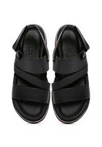 Zwarte sandalen met een gestructureerd, open ontwerp en brede banden. Zachte zool met een contrasterende rode accent langs de randen.