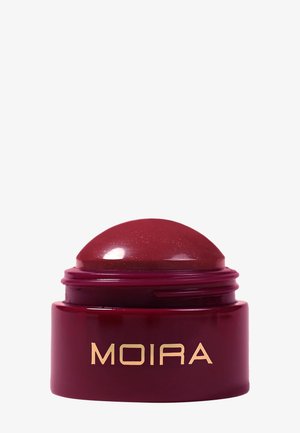 Deep red dome-shaped lip balm container with gold "MOIRA" branding on the front against a white background.