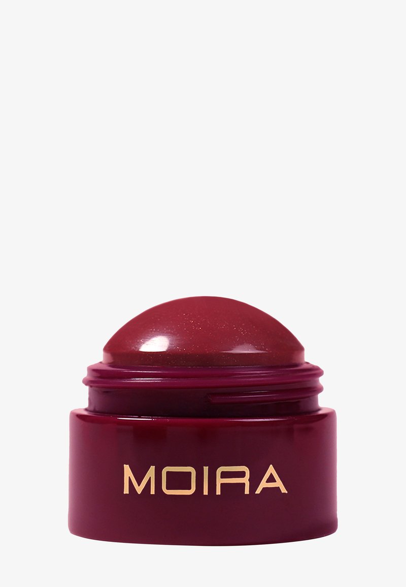 Petit contenant de baume à lèvres en forme de dôme rouge profond avec le logo "MOIRA" doré à l'avant sur un fond blanc.