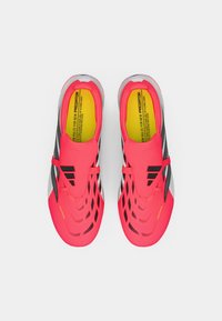 Φωτεινά ροζ αθλητικά παπούτσια με μαύρες λεπτομέρειες, υφή στο επάνω μέρος και αεροδυναμικό σχέδιο. Διαθέτουν επενδεδυμένο κολάρο και κίτρινες σόλες.