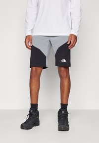 Melnas un pelēkas šortas ar ģeometrisku dizainu, izgatavotas no viegla auduma. Tām ir The North Face logo uz apakšējās kājas.