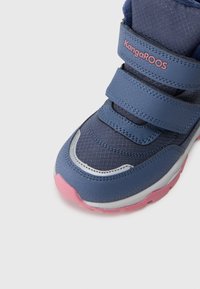 Blauer Sportschuh mit Klettverschlüssen, strukturiertem Synthetik-Obermaterial, rosa Akzenten auf der Sohle und silberner Verzierung an der Seite.