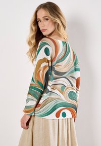 Maglione multicolore con motivi astratti a onde nei toni del verde, arancione e bianco. Design morbido con maniche a tre quarti. Maglia lavorata con texture.