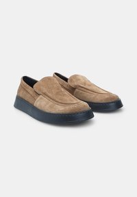 Bruine suede instappers met een ronde neus, voorzien van een donkerblauwe plateauzool en subtiele stikdetails langs de randen.