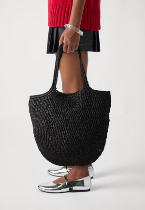 Zwarte gevlochten tote bag met een ronde vorm, dikke handvatten en een open bovenkant. Heeft een gestructureerd oppervlak en een aanzienlijke inhoud voor opslag.