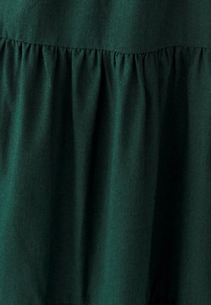 Tamsiai žalia medžiaga, turinti susiraukusį tekstūrą siūlėje, su lygiu paviršiumi ir subtiliu blizgesiu. Nėra matomų raštų ar papildomų detalių.