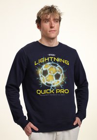 Mörkblå sweatshirts med en grafik av en fotboll med blixt-effekter och texten "OFFICIELL BLIXT SNABB PRO" i gult.