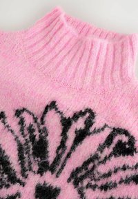 Rosa stickad tröja med hög ribbad krage. Har en svart blommönsterdesign. Mjuk textur med en fluffig look.