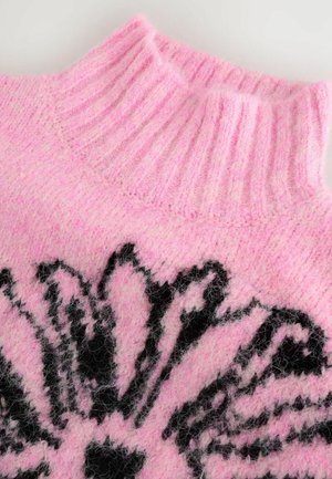 Pulover tricotat roz cu un guler înalt și ribborat. Prezintă un design floral negru. Textură moale cu un aspect pufoș.