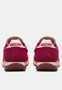 Scarpe da atletica in suede rosso con accenti bianchi, dotate di tacco imbottito e suola in gomma testurizzata. Logo visibile sulla linguetta del tallone.