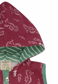 Burgunderfarbendes Oberteil aus Bio-Baumwolle mit weißem Seahorse-Muster. Ausgestattet mit einer grün gestreiften Innenkapuze und einem Reißverschluss. Größenlabel sichtbar.