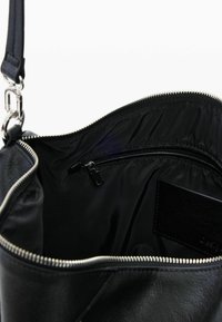 Mustast nahast käekoti sisu, sileda tekstuuriga, hõbedase tõmblukuga ja väike lukuga tasku tumeda voodriga.