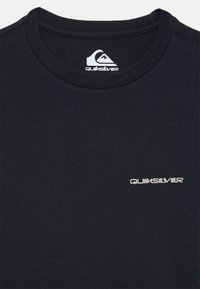 Juodas medvilninis marškinėliai su apvalia apykakle ir trumpomis rankovėmis. Priekyje yra baltas "Quiksilver" logotipas. Lygi tekstūra.