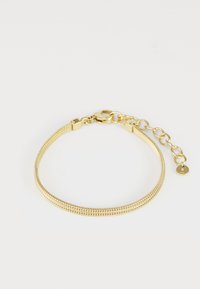 Pulseira de malha dourada com uma corrente suave e flexível e um fecho tipo lagosta. Apresenta um comprimento ajustável com um pequeno charme em forma de disco.