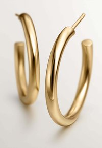 Pendientes de aro de oro con un acabado suave y pulido y un diseño ligeramente retorcido. Ligeros y de extremo abierto con un aspecto minimalista.